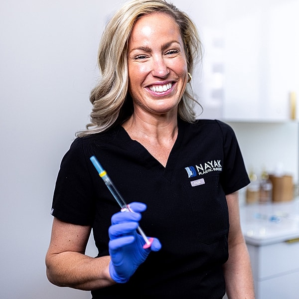 Smiling professional with syringe in medical setting.