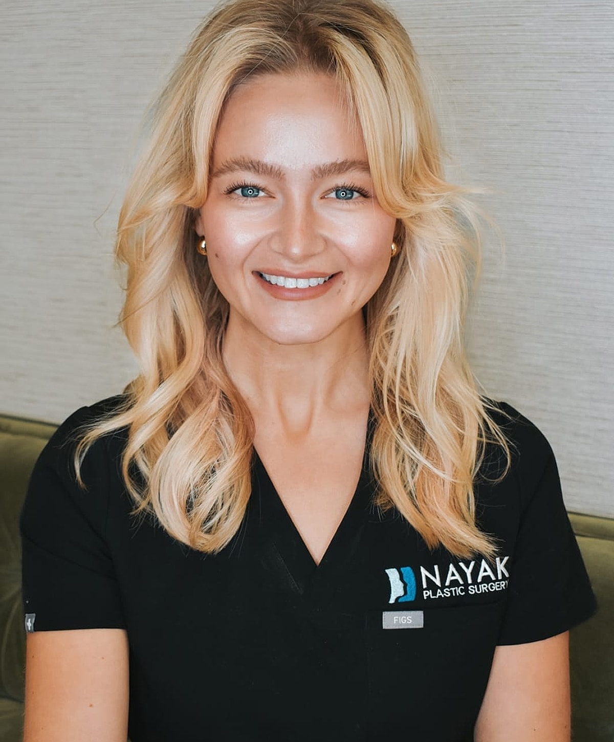 Smiling professional in plastic surgery scrubs.