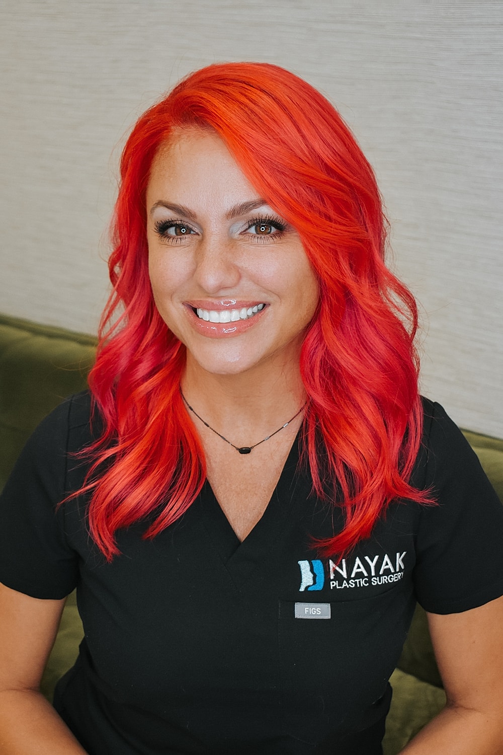 Woman with vibrant red hair smiling in scrubs.