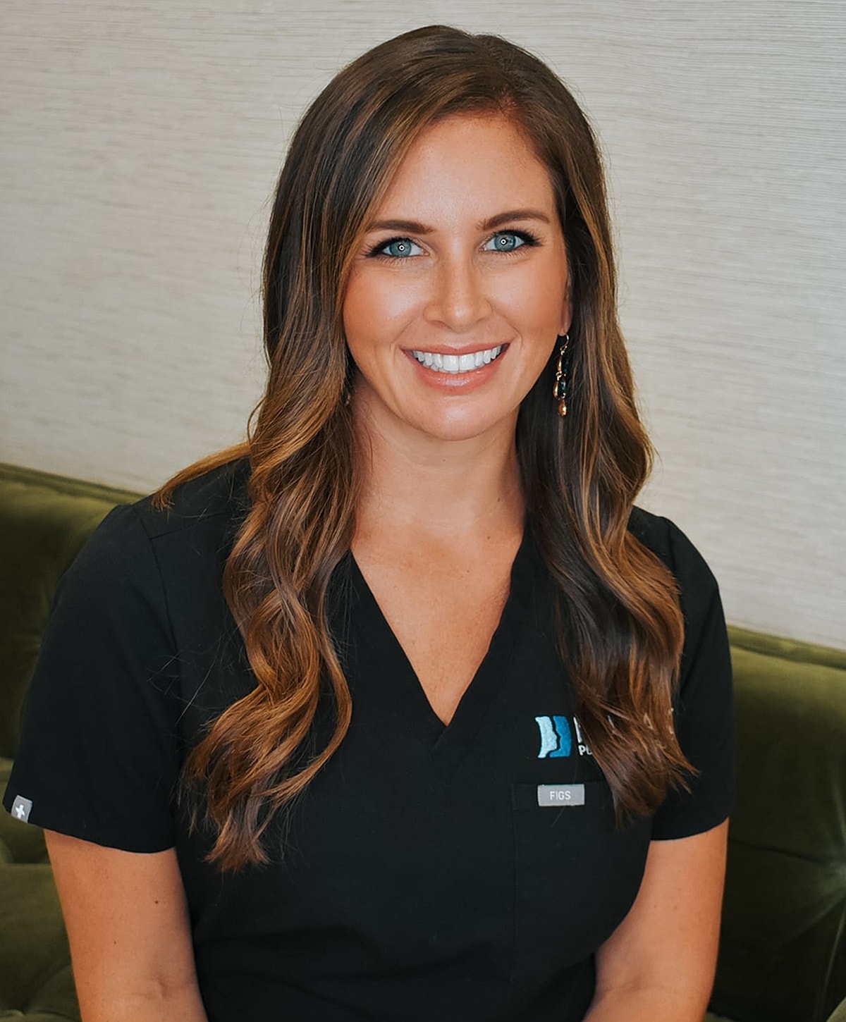Smiling woman in medical scrubs, professional setting.