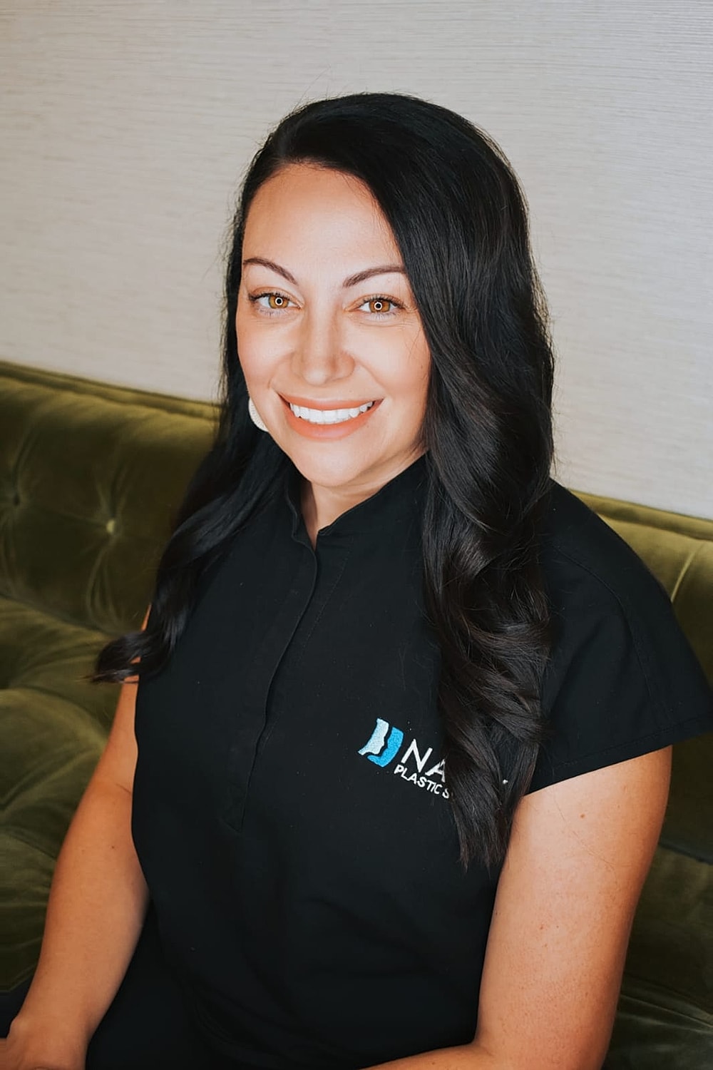 Smiling woman in professional attire, sitting indoors.